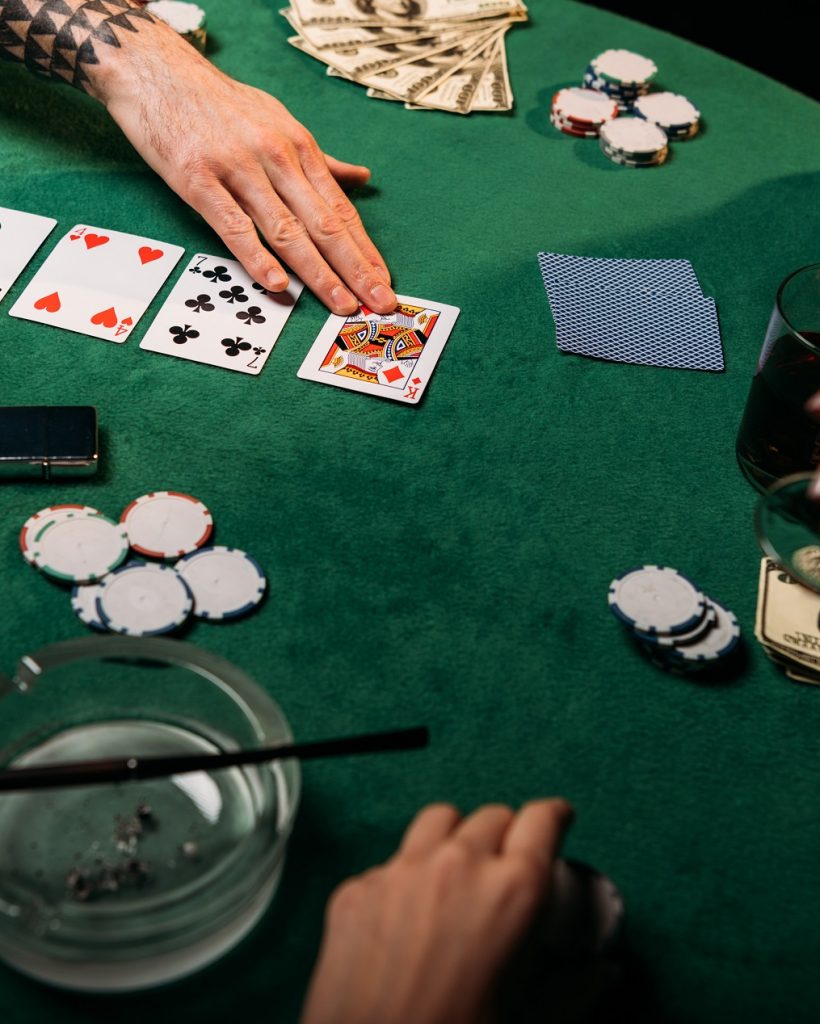cropped image of woman and tattooed man playing poker table in casino, girl holding glass of